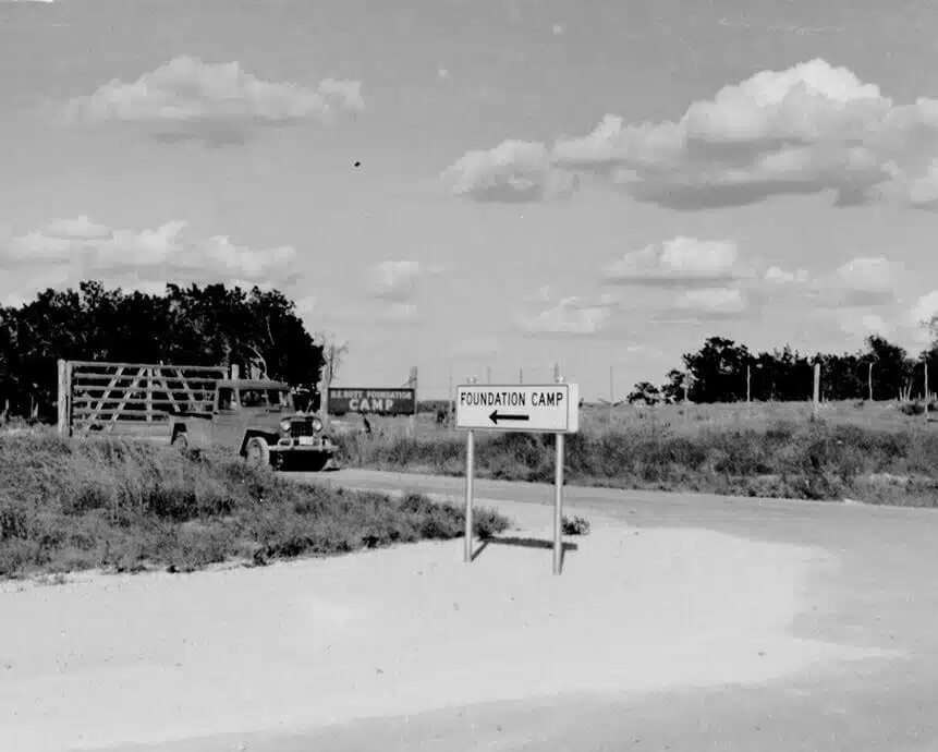 A 1950s truck at the gate with a sign pointing to Foundation Camp
